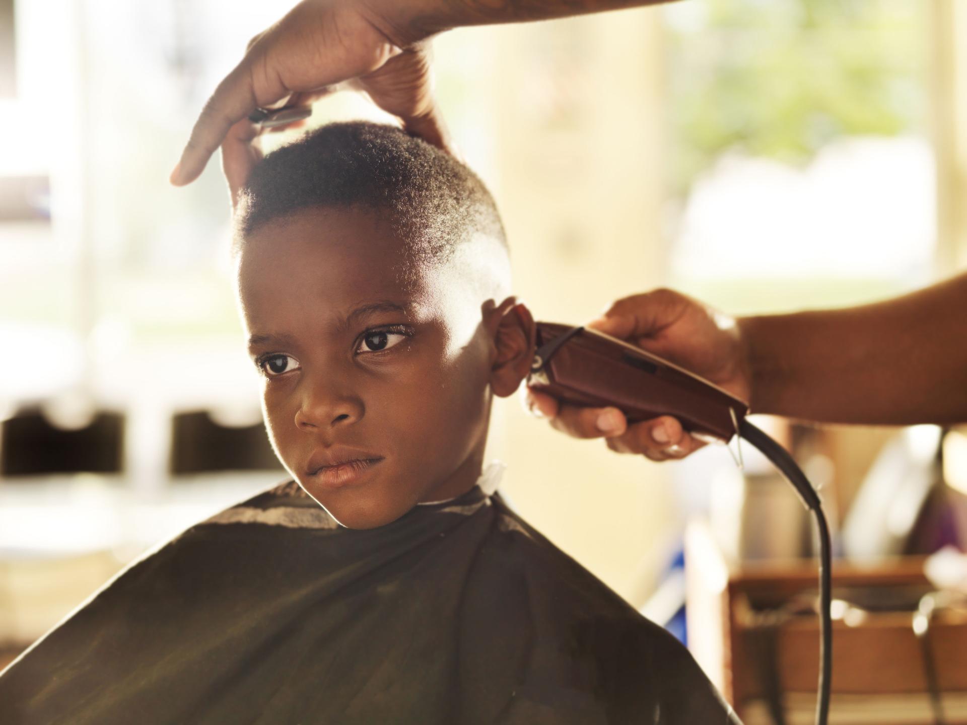 little boy getting his head shaved by barber