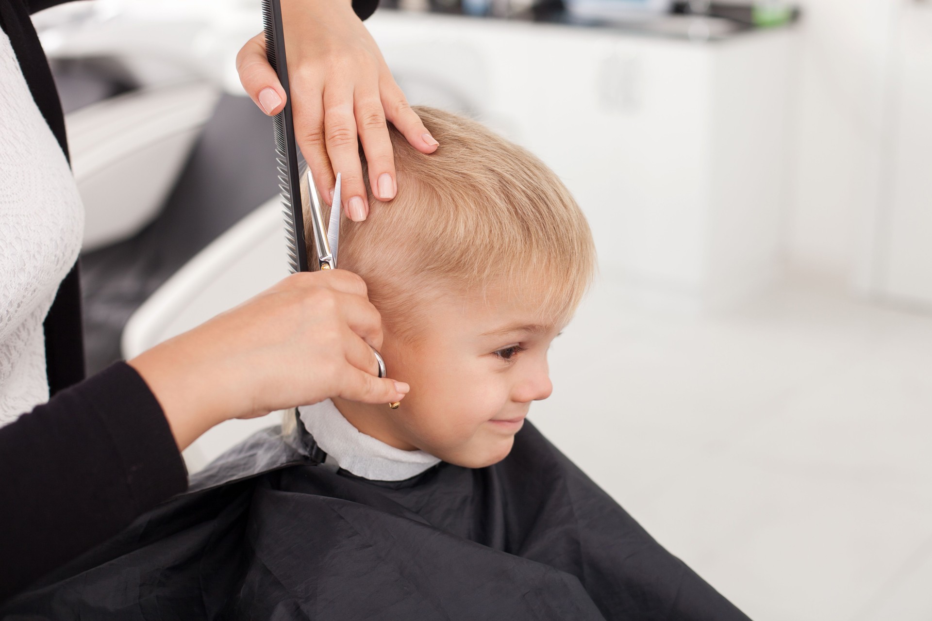 Skilled young female hairstylist is cutting human hair