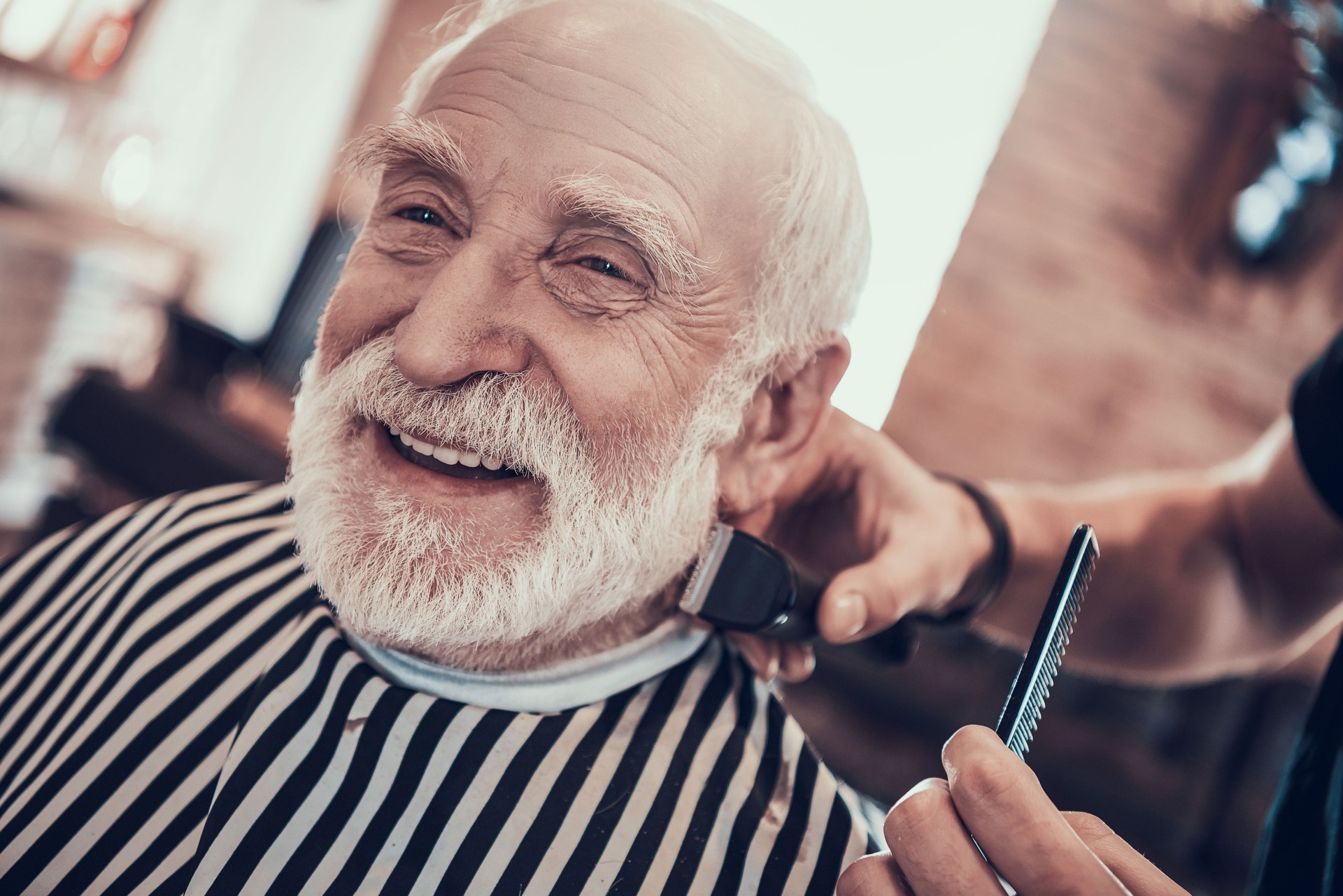 Grey Haired Adult Smiles During Nape Haircutting.